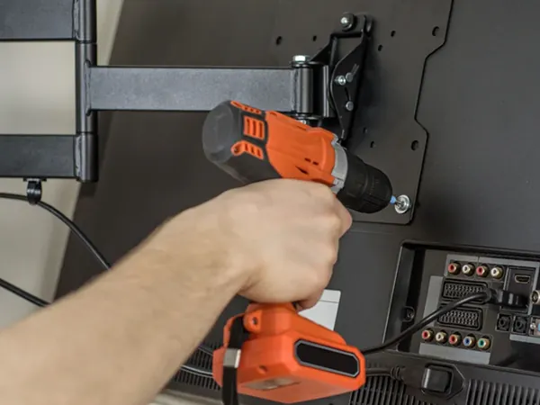 Technician drilling a TV wall mounting bracket